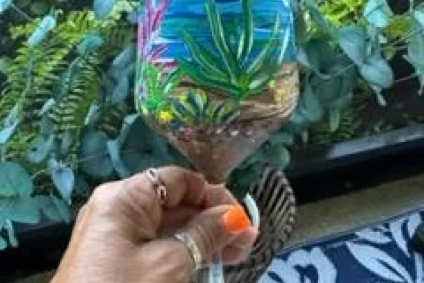someone holding a painted wine glass with an under water theme
